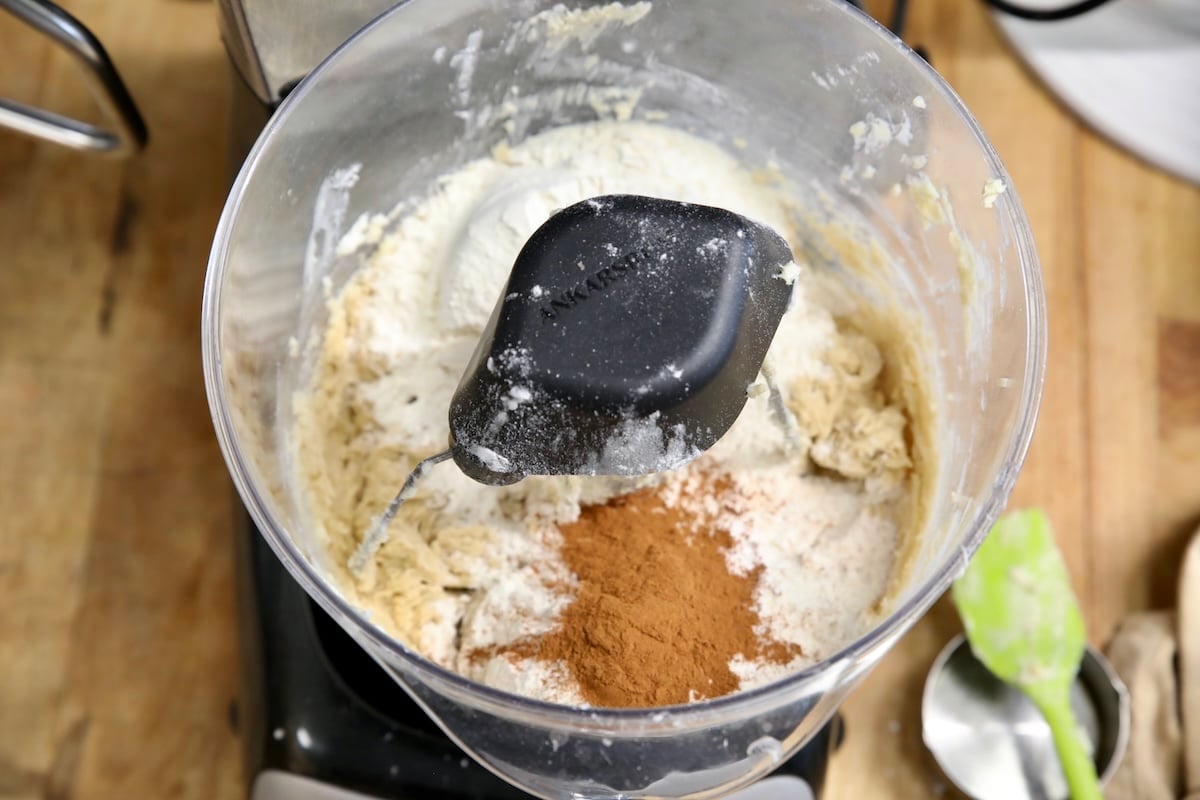 Mixer bowl of cookie dough with flour and cinnamon.