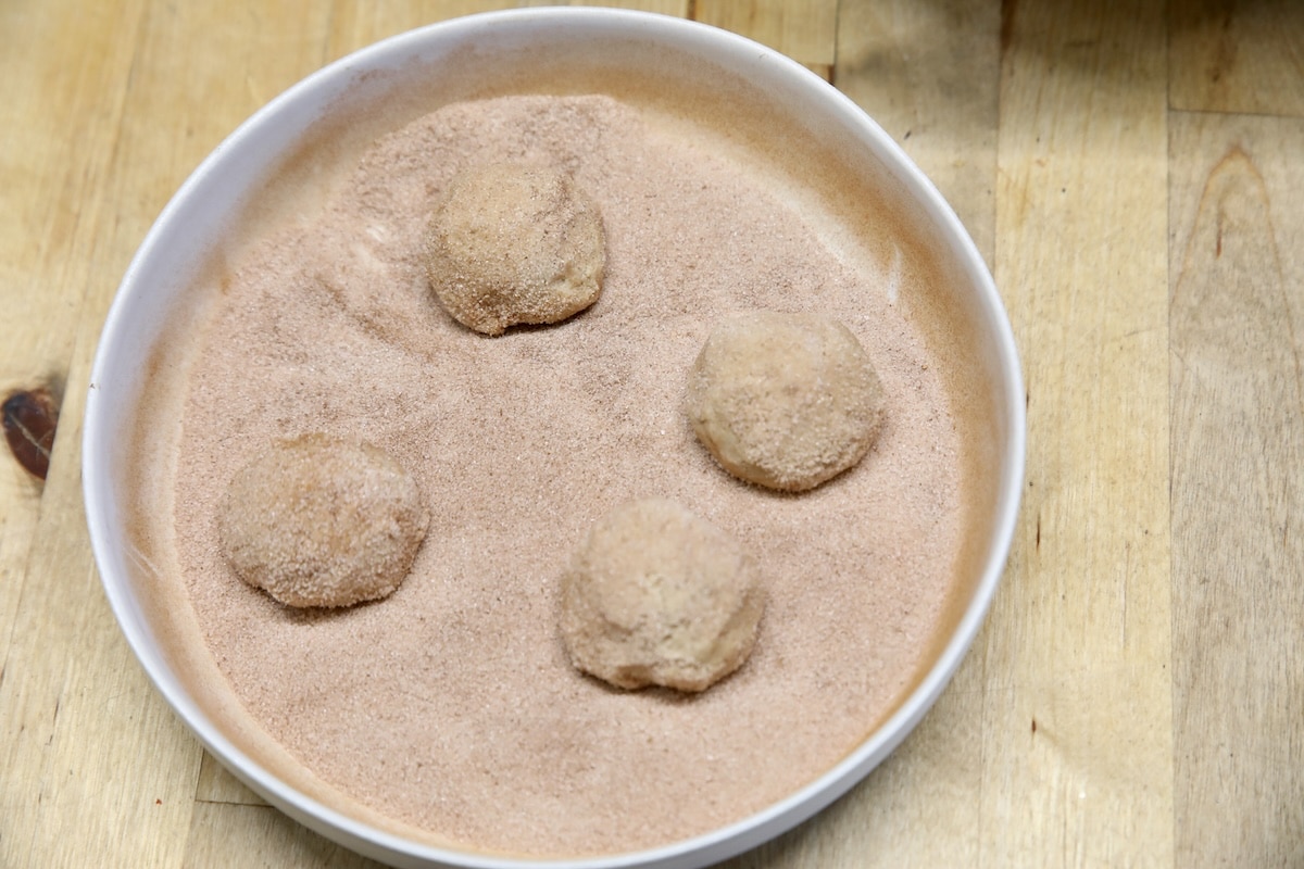 Bowl of cinnamon sugar with cookie dough balls.
