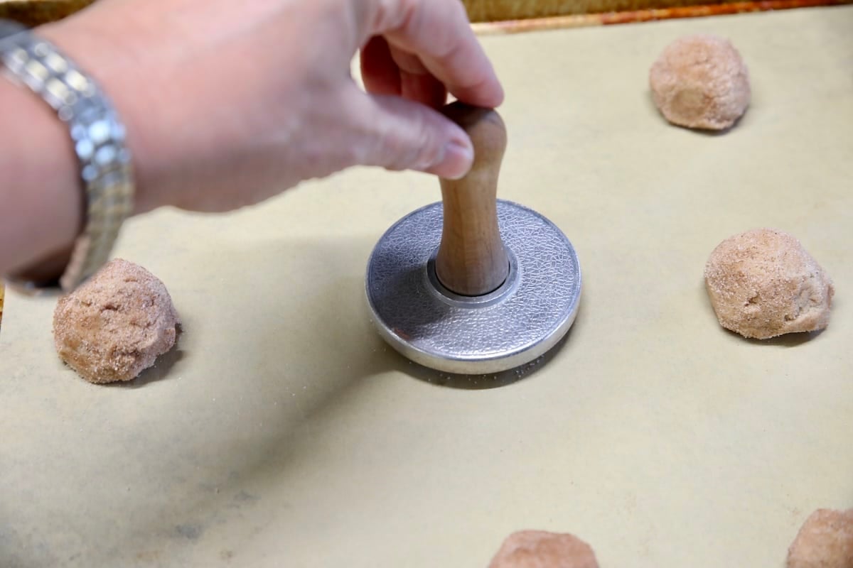 Smashing cookie dough with a cookie stamp.