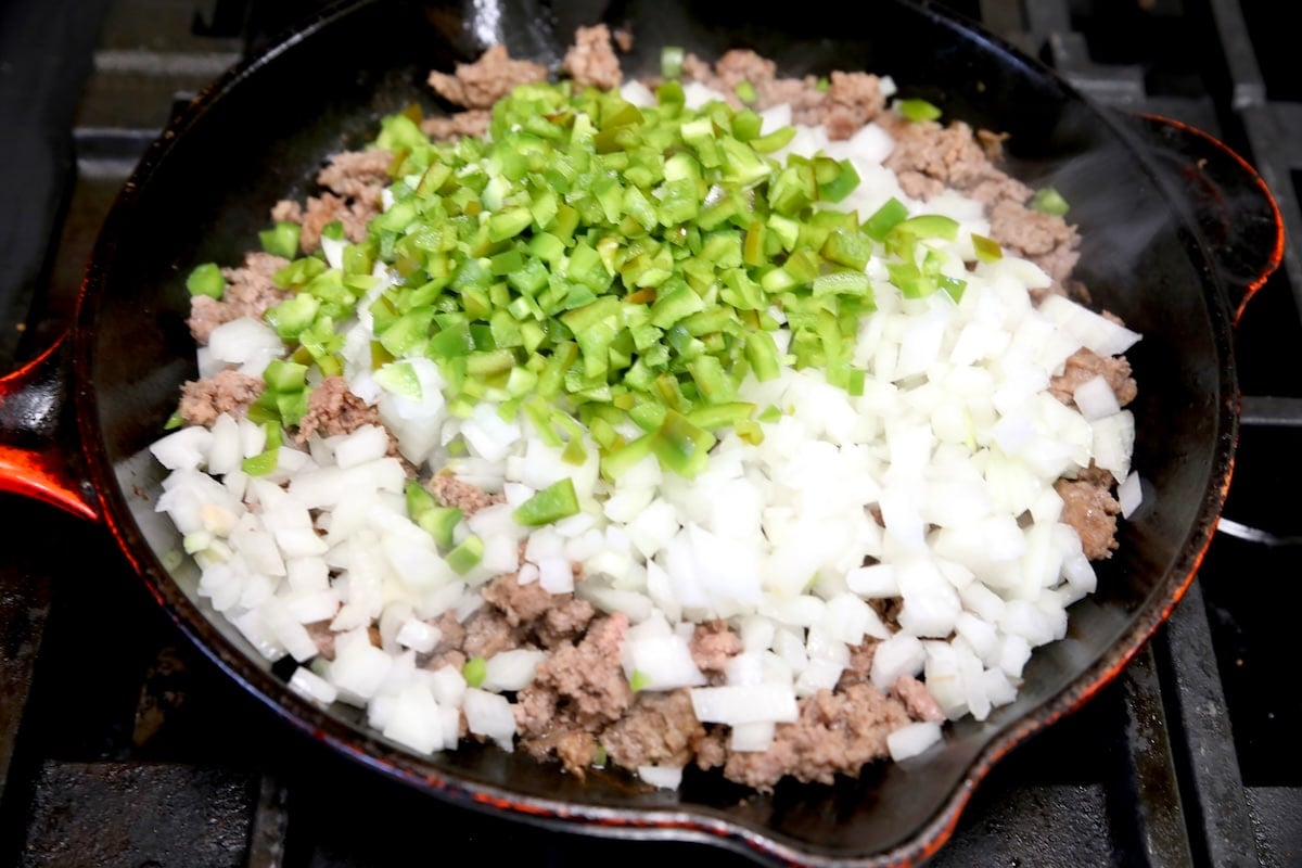 Diced onions and bell peppers in ground beef skillet.