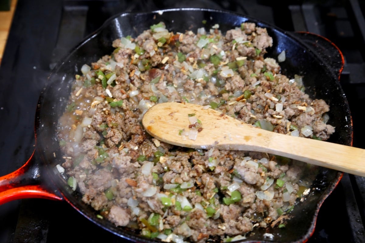 Making sloppy joes in a skillet with wooden spoon.