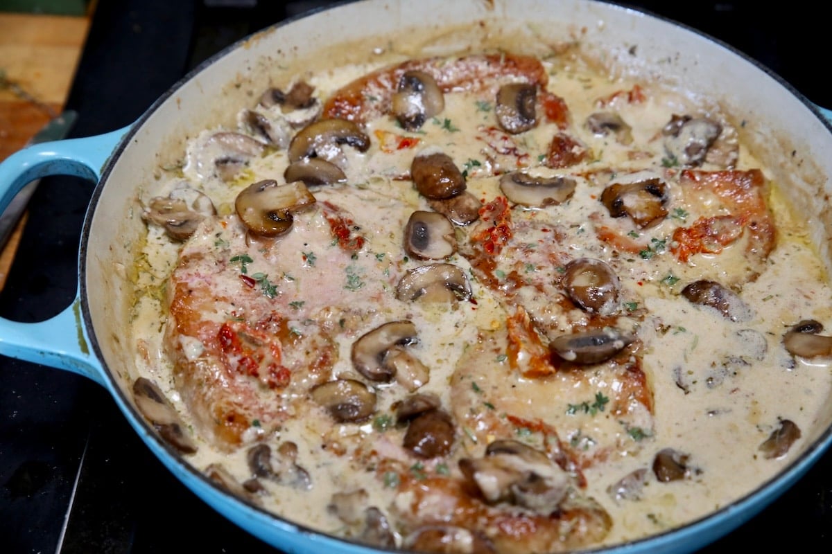 Pork chops with mushroom cream sauce in a skillet.