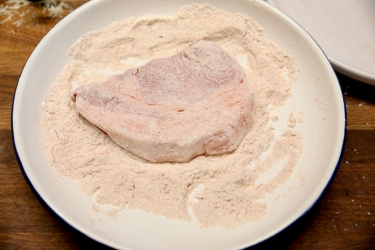 Dredging pork chops in seasoned flour.