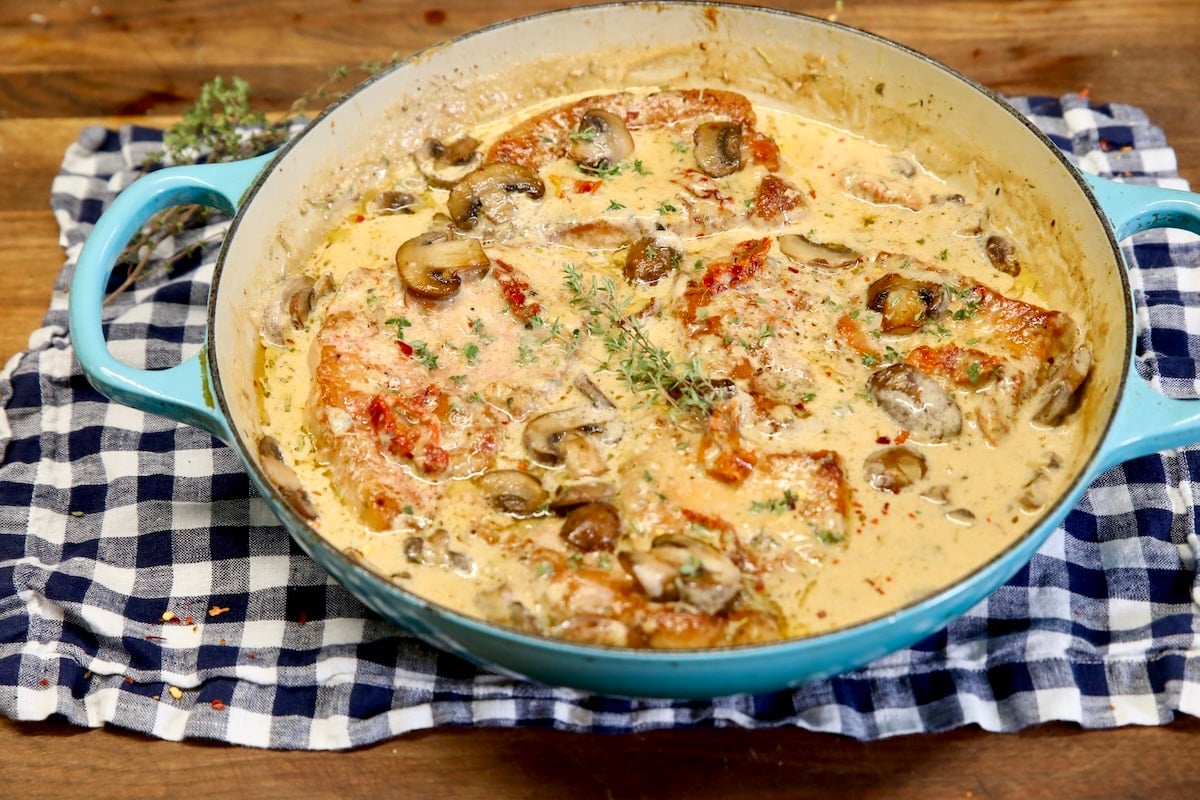 Pan of pork chops with cream sauce and mushrooms.