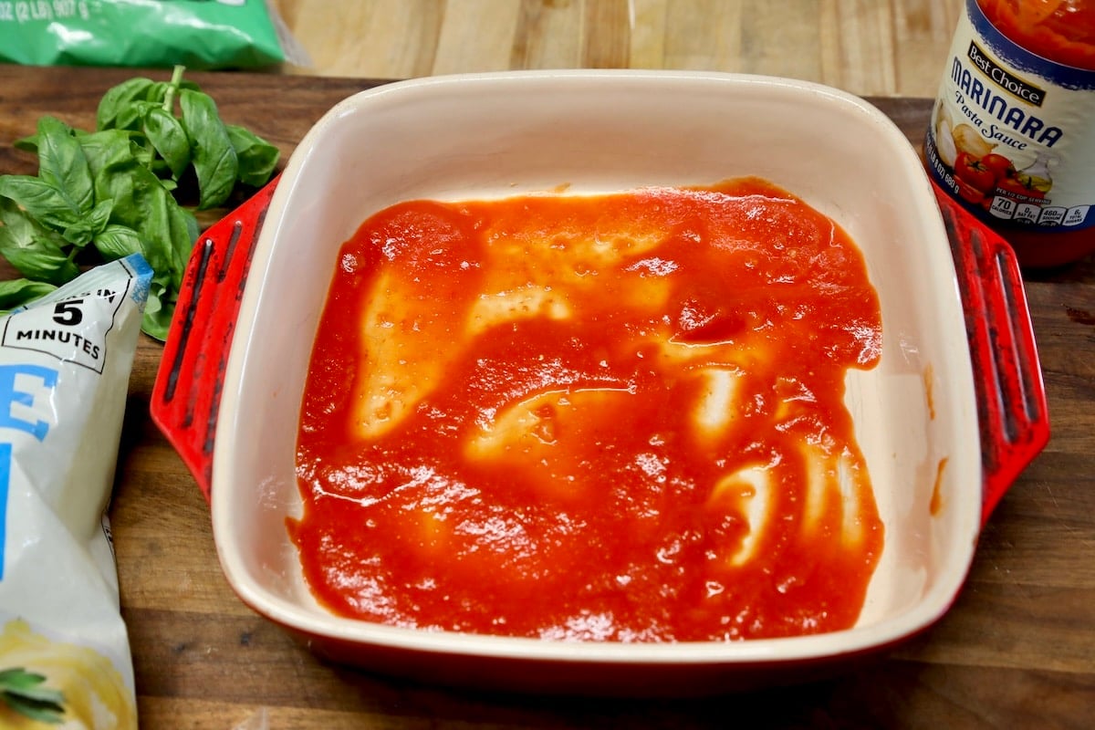Square casserole dish with marinara sauce.