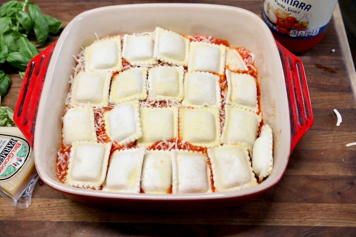 Layering ravioli, sauce and cheese in casserole.
