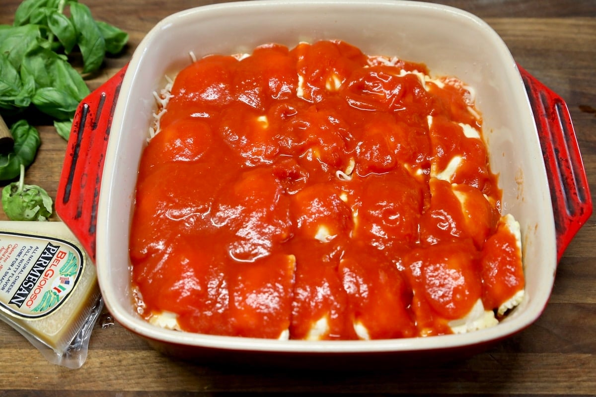Marinara and ravioli layered in casserole.