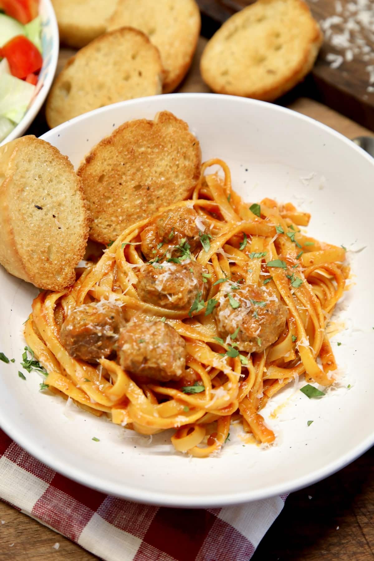 Bowl of spaghetti and meatballs with garlic bread.