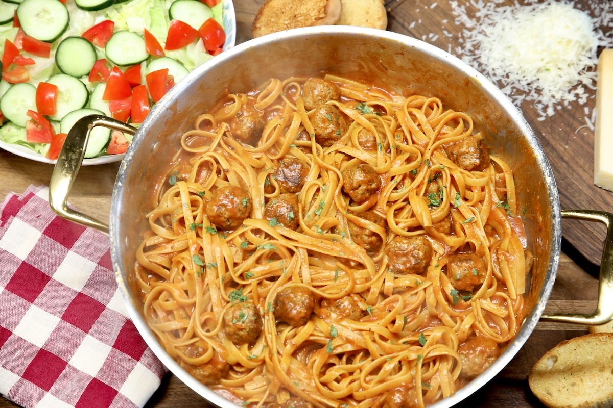 Pan of spaghetti and meatballs, bowl of salad.