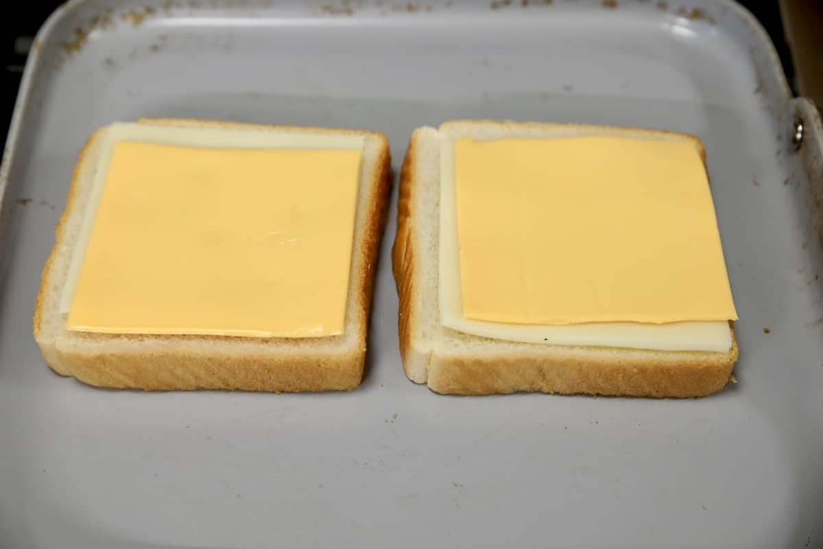 2 slices bread with cheese on a griddle.