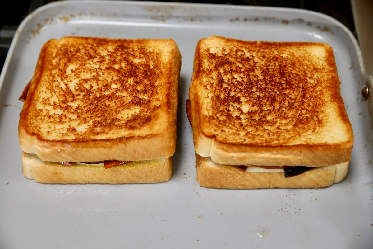 2 Golden brown grilled cheese sandwiches on griddle pan.