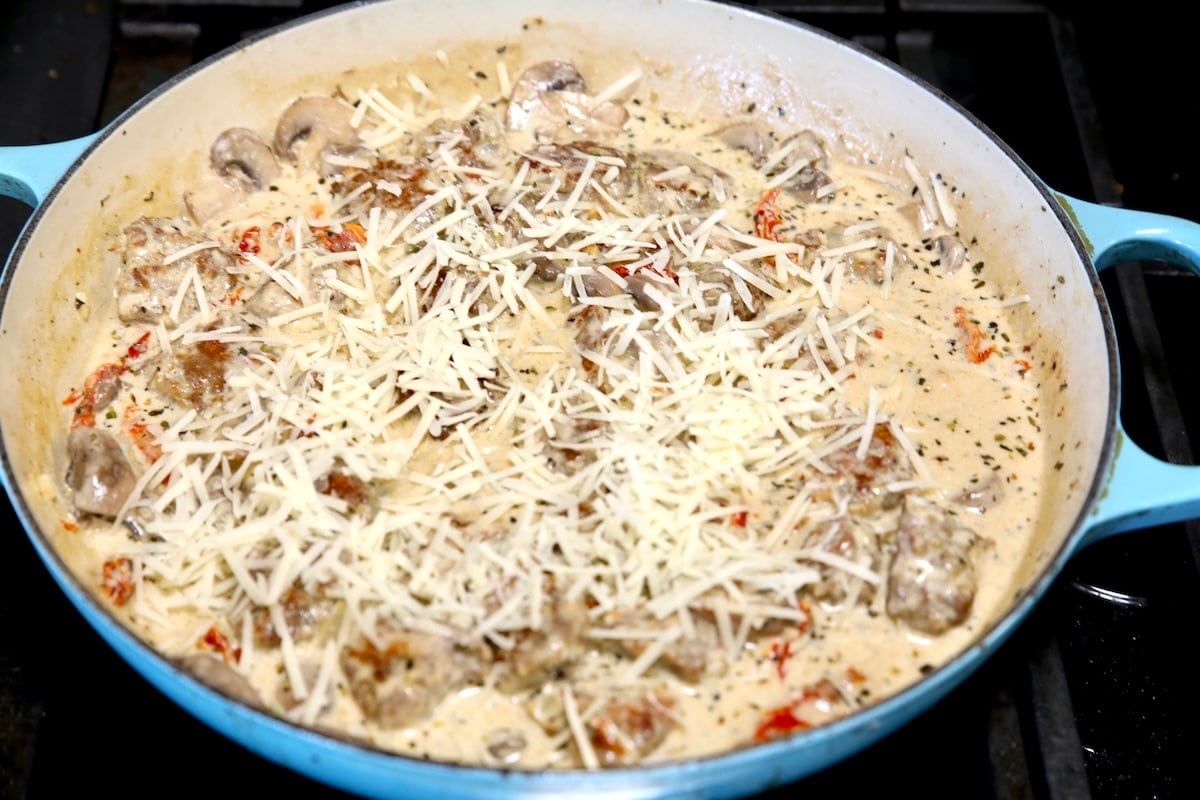 Creamy meatballs in a skillet with parmesan cheese.