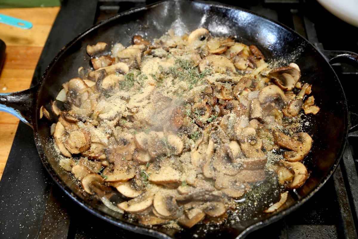 Seasoning mushrooms in a skillet.
