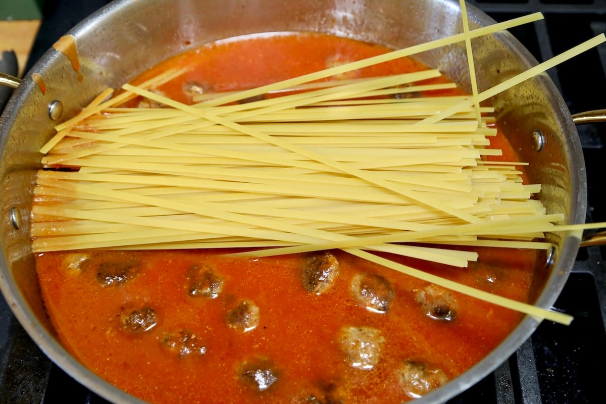 Pasta in a pan with meatballs and marinara.