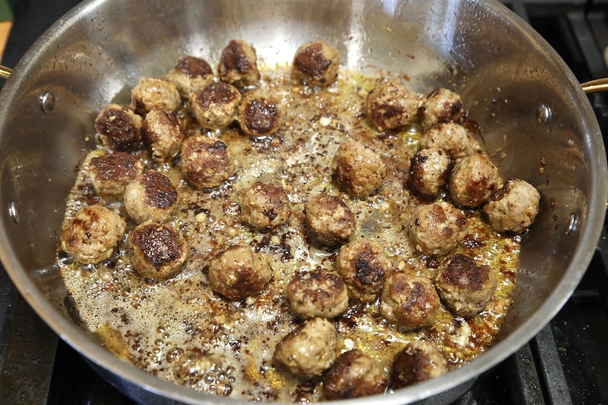 Browned meatballs in a skillet.