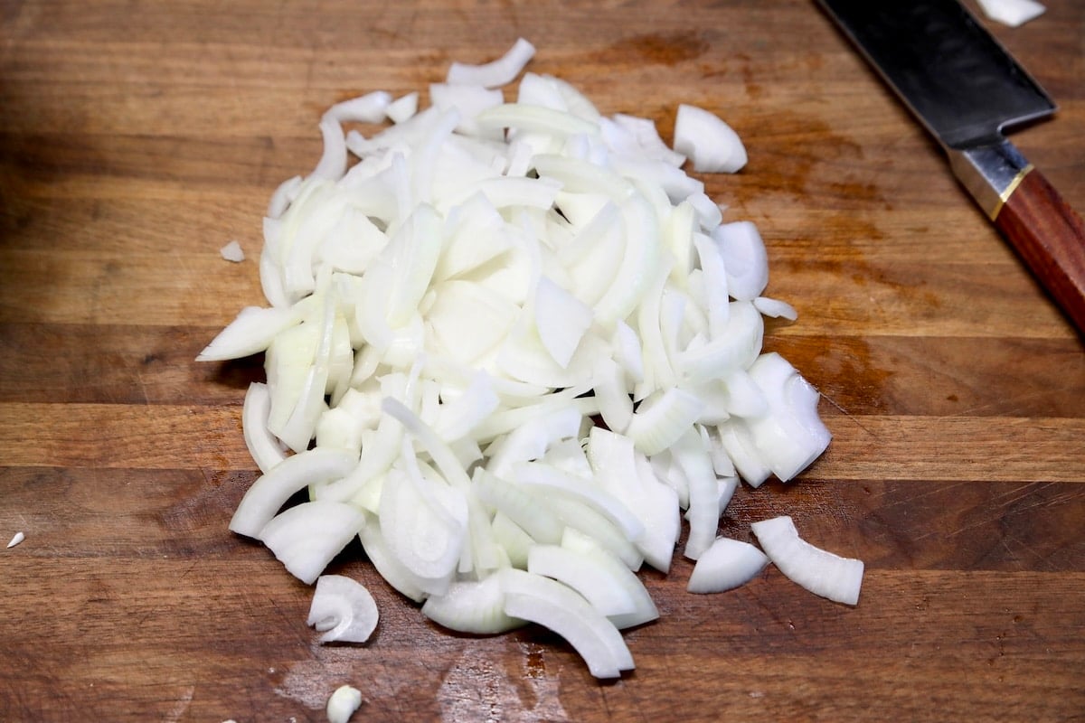 Sliced onions on a wood board.