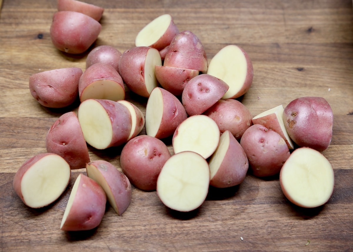 Baby red potatoes cut in half on board.