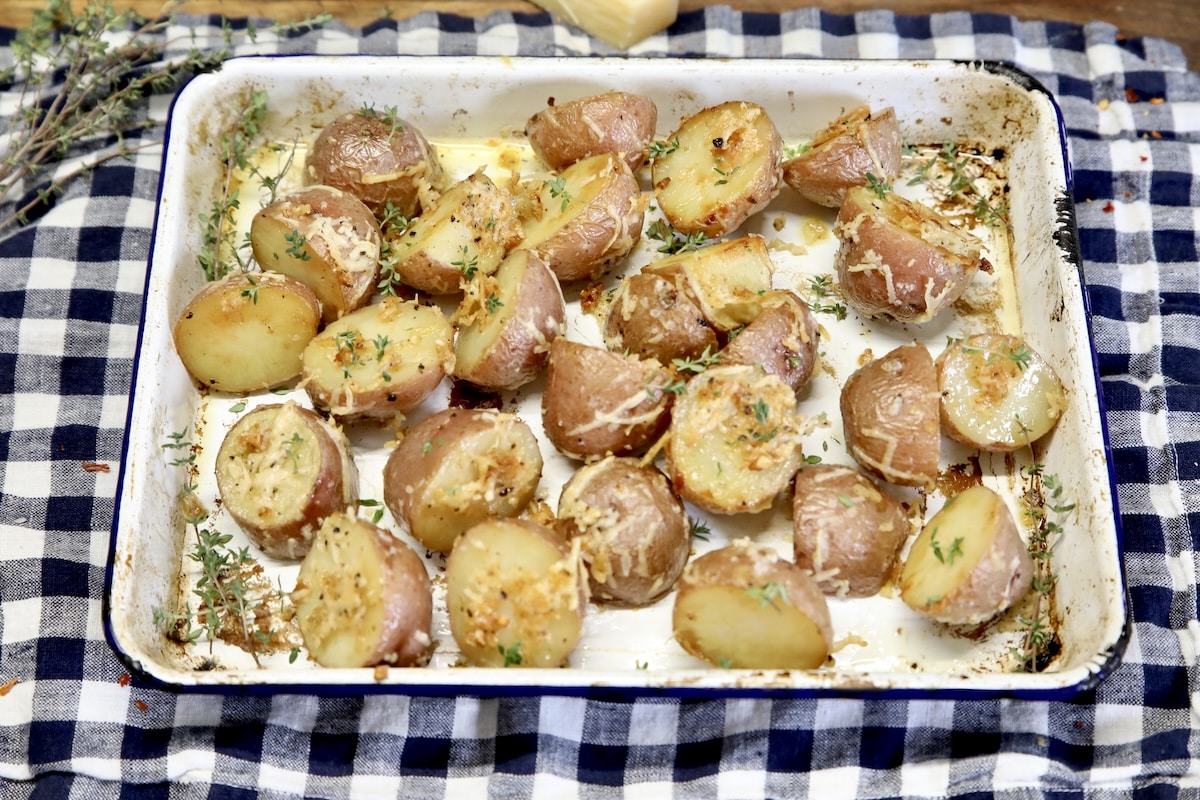 Parmesan and garlic roasted potatoes. Pan of roasted parmesan potatoes on a checked cloth.