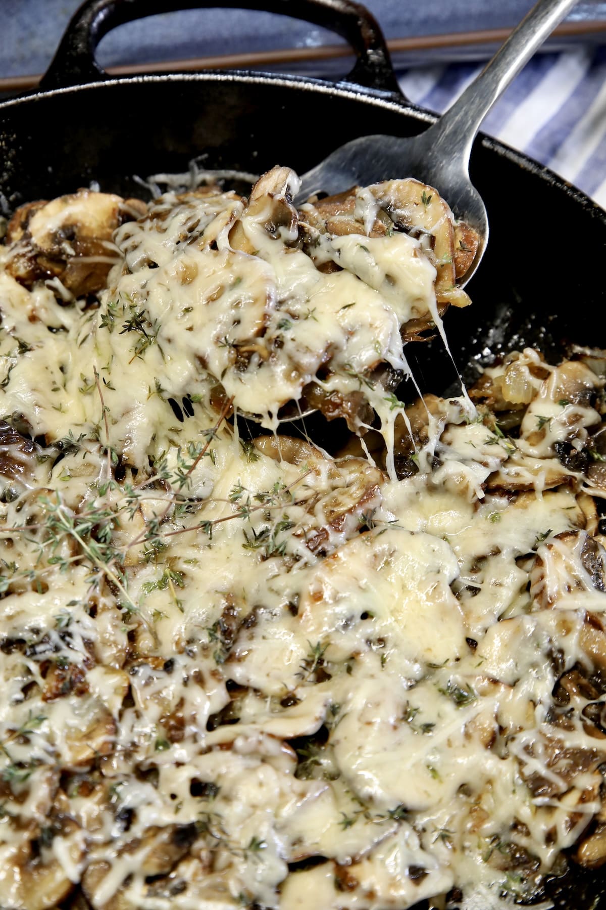 Skillet of mushrooms with cheese - spoonful.