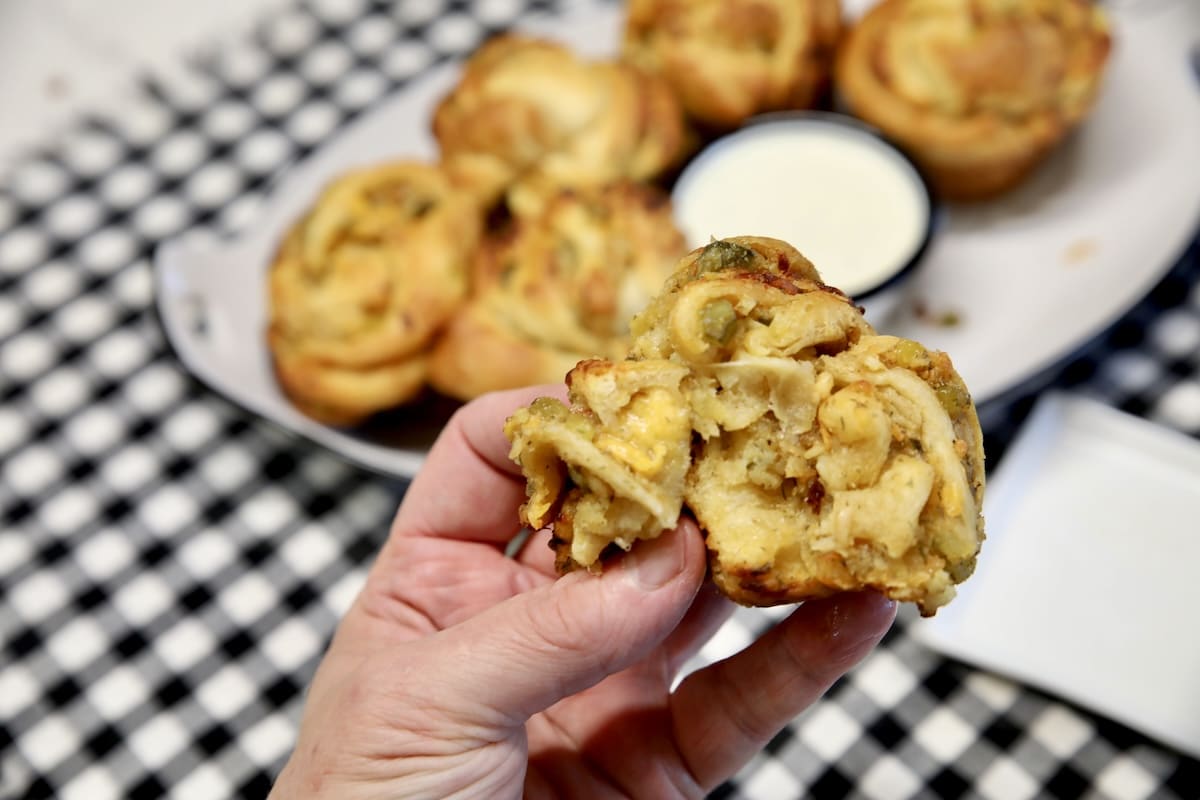 Cheesy pickle cruffin held in hand.