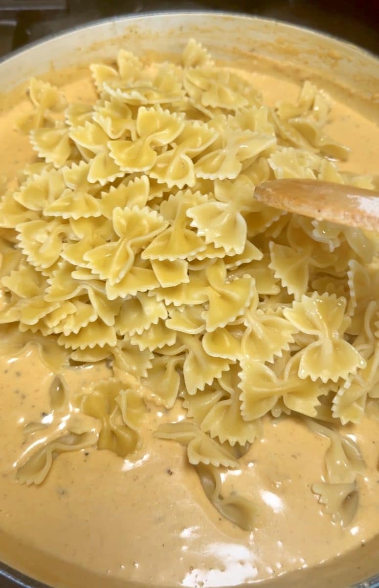 Adding pasta to cheese sauce.