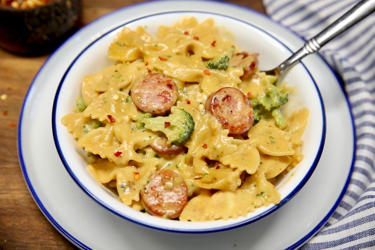 Bowl of cheddar pasta with broccoli and smoked sausage.