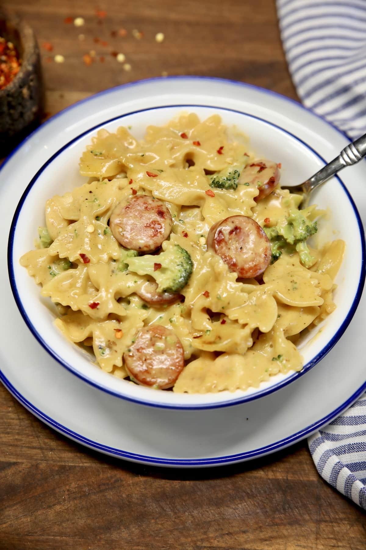Bowl of cheesy pasta with broccoli and smoked sausage.